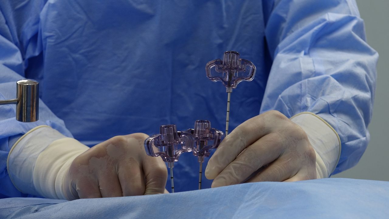 Close-up of a surgeons hands wearing gloves and operating tools in a sterile environment.